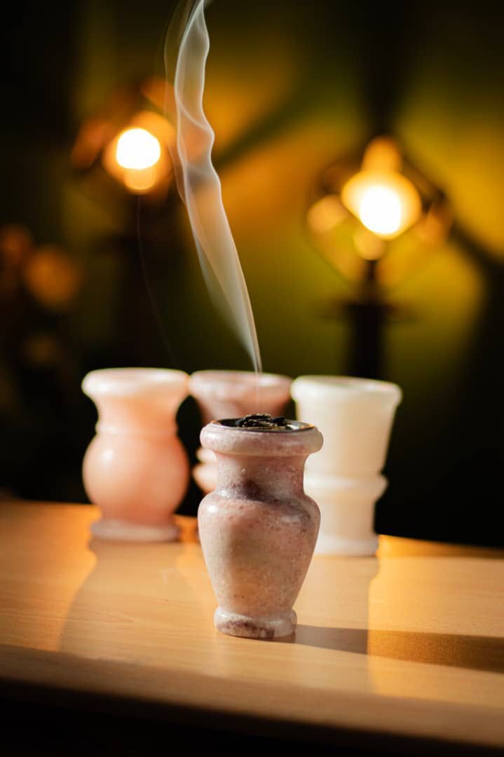 Pink salt incense burner made from natural mineral salt, releasing aromatic smoke in
